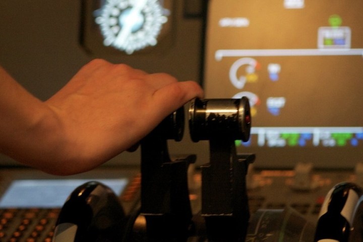 a hand holding a remote in front of a computer